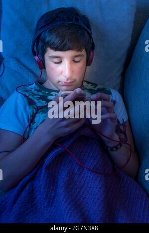 Teenage boy on his phone in bed,UK Stock Photo