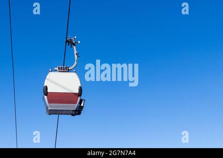 Closed cableway cabin in the air. Against the background of blue sky. Copy space to the right. Bottom view Stock Photo