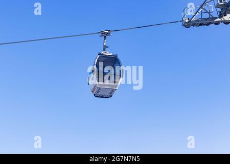 Transparent glass cableway cabin against blue sky near rollers Stock Photo