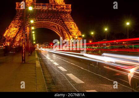 France, Paris. Traffic on the Jena bridge. Night at the foot of the Eiffel Tower. Many light trails from car headlights Stock Photo