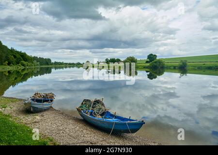 Salmon netting boats on the River Tweed at Paxton in  the Scottish Borders on a sunny summers day with stunning reflections of the sky in the river. Stock Photo