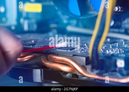 Internal parts of an old personal computer. Dusty motherboard and video card. The wizard cleans the video card. Broken PC Stock Photo