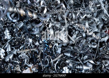 Steel scrap materials recycling. Aluminum, iron chip waste after machining metal parts on a cnc lathe. Closeup abstract twisted spiral steel shavings. Stock Photo