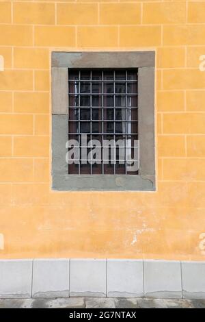 Closed square window with metal fence on stone house wall facade Stock Photo