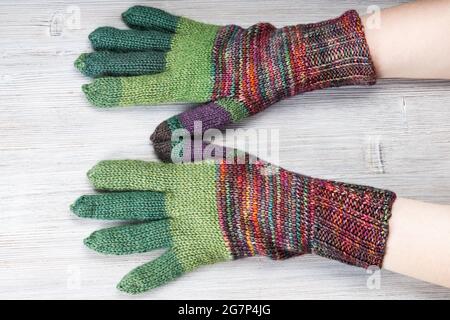 back view of female hands in knitted gloves on gray table Stock Photo