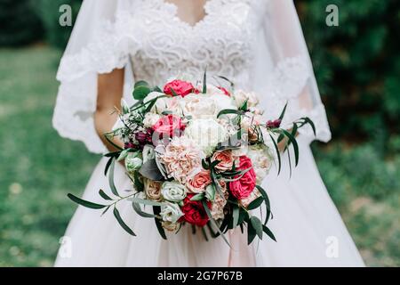 Beautiful bride with a amazing wedding bouquet of red, white, beige roses Stock Photo