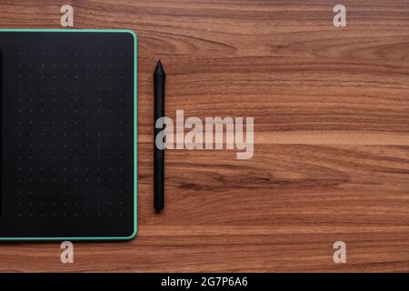 Top view of a graphics tablet with a pen on a wooden table Stock Photo