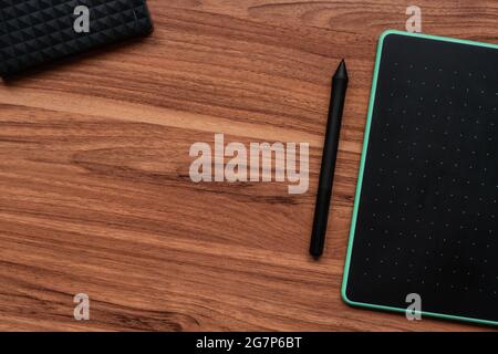 Top view of a graphics tablet with a pen on a wooden table Stock Photo