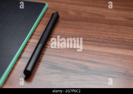 Closeup of a graphics tablet with a pen on a wooden table Stock Photo