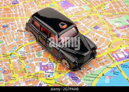 A  black cab taxi, on a map of London city. Stock Photo