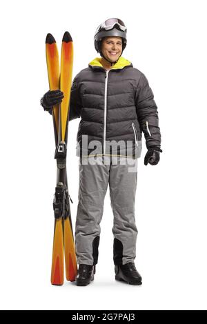 Full length portrait of a man in a skiing jacket and boots holding pair of skis isolated on a white background Stock Photo