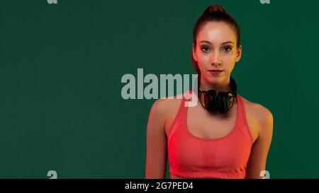 Young smiling sportive girl listening to music on headphones after playing sports exercise Stock Photo