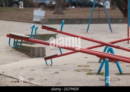 Picture of a kids teeter totter in a playground, empty, with a focus on the seating. A seesaw (also known as a teeter-totter or teeterboard) is a long Stock Photo