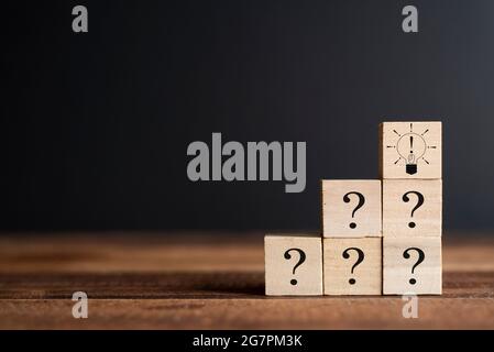 Question mark and Exclamation mark bulb on a wooden cube. Concept of FAQ, Questions and answers, Brainstorming and teambuilding Stock Photo