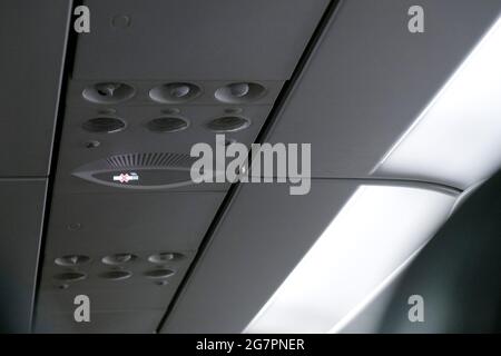 no smoking sign lit up on the ceiling of airplane cabins above passenger seats that cigarette is prohibited in flight Stock Photo