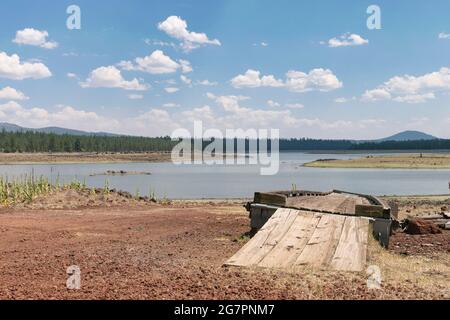 Thompson Reservoir in Lake County, Oregon is at low levels during extreme drought. A boat dock remains far from the receding shore. Stock Photo