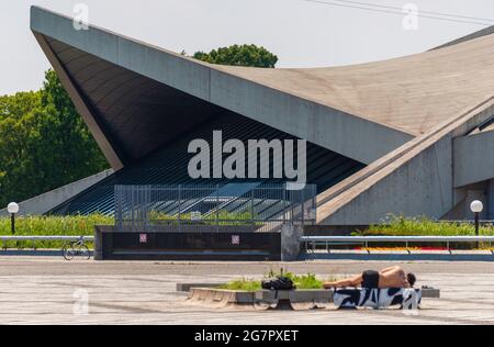 A man sunbathes in front of the gymnasium inside Komazawa Olympic Park, Tokyo on 10 June 2021. The park was built for the 1964 Tokyo Olympics. Robert Gilhooly photo Stock Photo