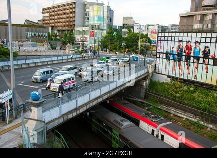 Pedestrians pass over the Olympic Bridge near Yoyogi Park, Tokyo on 21 June 2021. While the bridge was part of a new road system that was built prior to the 1964 Olympics, the globes atop the pillars and Olympics-themed stone reliefs were added more than 25 years later. The bridge is located close to Japan's youth culture center, Harajuku, which gained increasing popularity as an alternative culture center following the 1964 Games. Robert Gilhooly photo Stock Photo