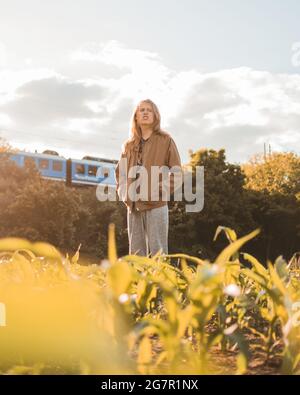 Young Caucasian male in casual wear standing in a field Stock Photo