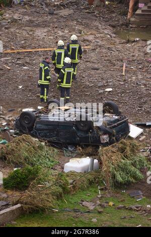 Bad Neuenahr Ahrweiler, Germany. 16th July, 2021. Firefighters walk past a destroyed car in the community of Schuld the day after the flood disaster. Heavy rain led to extreme flooding. Credit: Thomas Frey/dpa/Alamy Live News Stock Photo