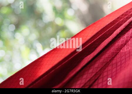 Shallow depth of field of a folded red curtain with wooden frame on a window with green bokeh background for copy space and wallpaper Stock Photo