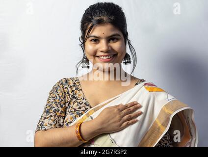Isolated on white background an Indian female in saree touching her heart with smiling face on white background Stock Photo