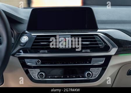 Premium car interior with multimedia display and dashboard. Control panel, radio system, air conditioning button and start stop button. Stock Photo