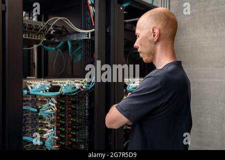 Man data center technician performing server maintenance. Looking to hardware rack Stock Photo