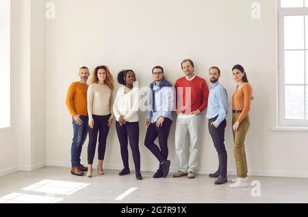 Group of diverse people in casual wear standing together in empty office or studio Stock Photo