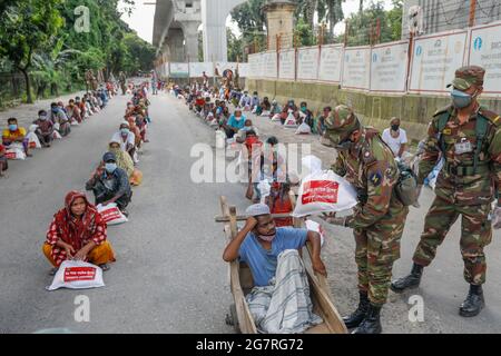 Low income people receive emergency food items provided by Bangladesh Army during the nationwide lockdown to curb the spread of coronavirus (COVID-19) Stock Photo