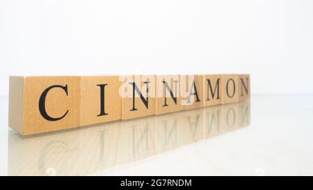 The word Cinnamon was created from wooden letter cubes. Gastronomy and spices. close up. Stock Photo