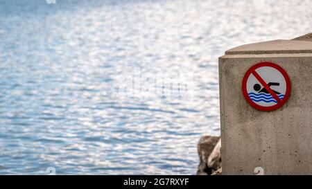 No swimming sign beside water. Stock Photo