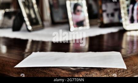 White closed envelope on wooden table , in the background several silver photo frame Stock Photo