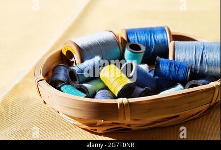 Spools of blue thread and one yellow spool in basket ,different size spools Stock Photo