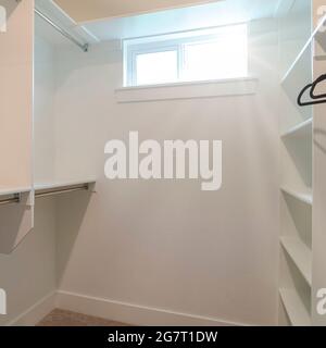 Square frame Walk in closet of a new home with empty wall shelves and garments rods Stock Photo
