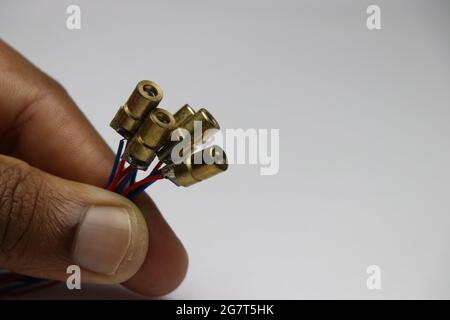 Group of copper case red dot laser diodes held in hand. Electronic components for laser light experiments Stock Photo