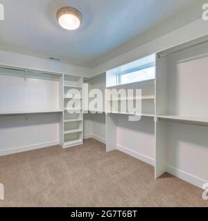 Square frame Walk in closet of house with empty built in shelves and two levels clothing rods Stock Photo