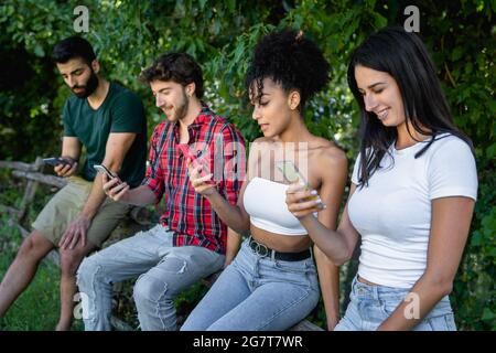 Millennials using smartphone in the countryside. Multiracial group of young people using tech in nature concept. Stock Photo