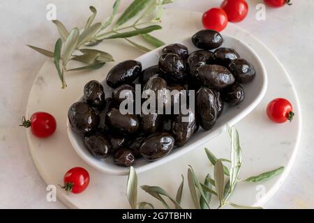 Black kalamata olives. Tasty organic kalamata olives in the plate. Olive on marble floor Stock Photo