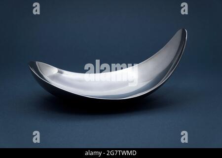 Empty metal silver plate on dark grey background. Stock Photo