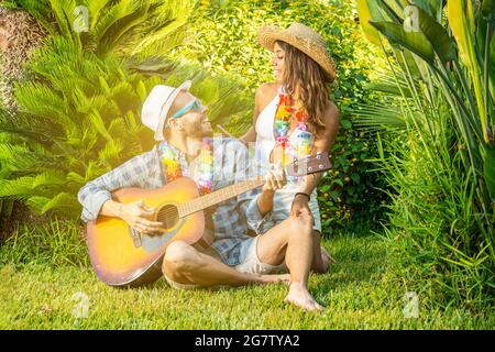 young couple in love sitting on the grass playing the guitar. concept of love and happiness Stock Photo