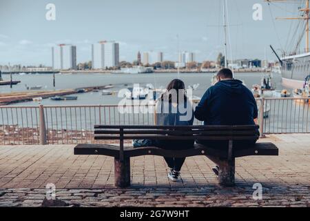 A couple sitting on a bench together at the seaside Stock Photo