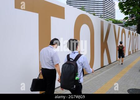 Tokyo, Japan. 15th July, 2021. People walk past a large Tokyo 2020 sign around the National Olympic stadium, Gaiemmae. The Tokyo Olympic Organizing committee is planning to open the delayed Games on July 21st despite uncertainty on what measures to take to ensure safety for athletes, spectators and the local population in the continuing COVID-19 pandemic. Credit: SOPA Images Limited/Alamy Live News Stock Photo