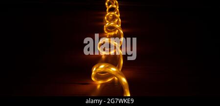 glowing strip of LED decorative lighting in warm yellow color on a dark background. Stock Photo