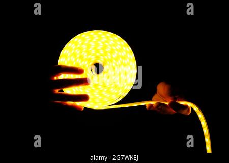 led lighting logo, LED strip in hands in the dark. Stock Photo