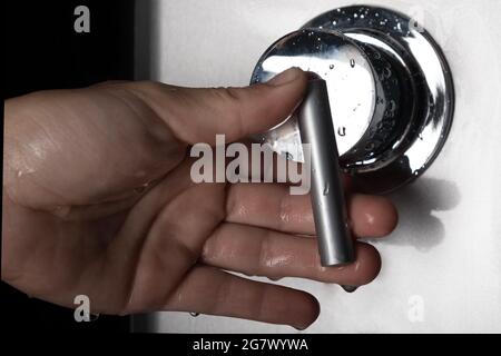 hand switches shower mixer for switching between hot and cold water. Stock Photo