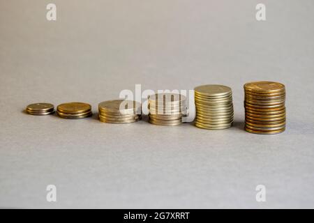Coins of different sizes and denominations stacked in ascending piles on gray background. Cash. Numismatics. Concept of investment, currency exchange Stock Photo