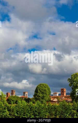 Lucca charming historic center skyline with beautiful clouds and medieval towers rises above surrounding anciet walls park trees Stock Photo