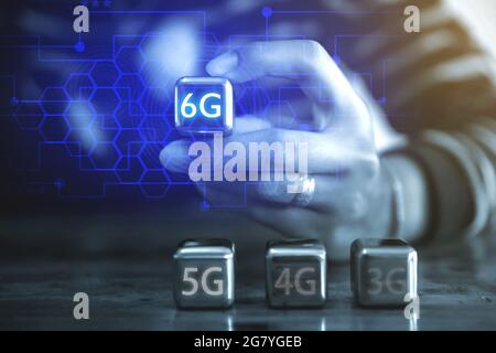 6G Internet and network technology concepts A young businessman using a square steel ball hand and sees the inscription: 6G using a steel ball mobile. Stock Photo