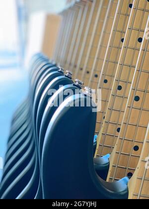 a closeup of a lineup of bass guitars on a rack Stock Photo